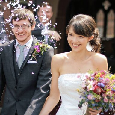 Happy couple leaving the church after their wedding. The bride shows off professional makeup application