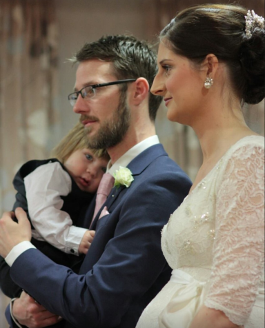Altar shot of man and wife with small child showing bridal makeup from the side profile