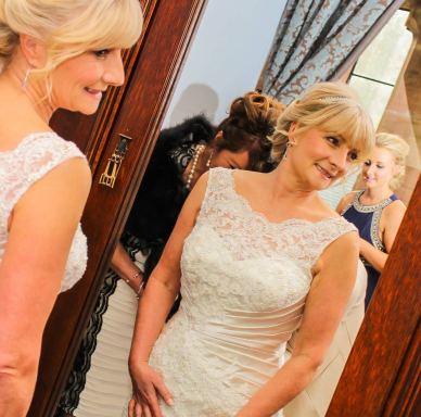 Mature bride smiling in mirror after stunning bridal makeup application in Cheshire