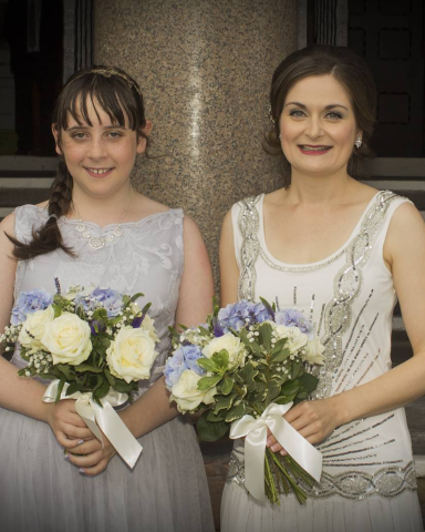 A bride and her flower girl, smiling at the camera after a Chester wedding at Chester Town Hall. Makeup is 20s vintage and natural.