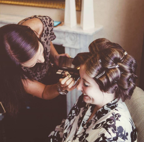 Kirsty applying professional makeup to a smiling bride in the Chester Grosvenor Hotel, Chester, Cheshire.