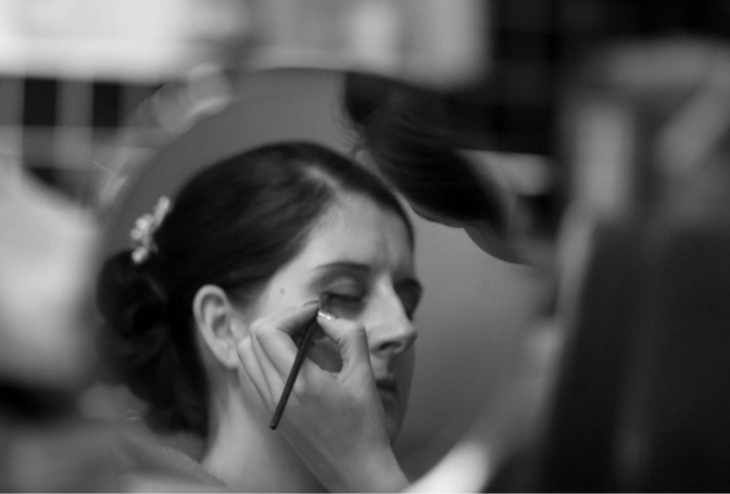 Kirsty applying makeup to bride in black and white image